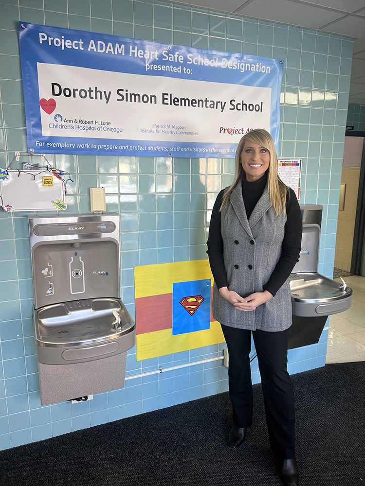 Woman standing next ot Dorothy Simon Elementary School poster